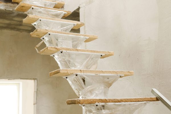 Unfinished wooden stairs to second floor in new building. Construction of house and home renovation concept
